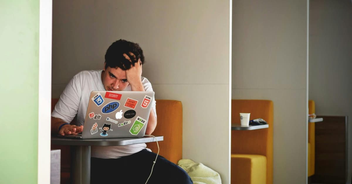 Freelancer frustrated checking unpaid invoice on laptop