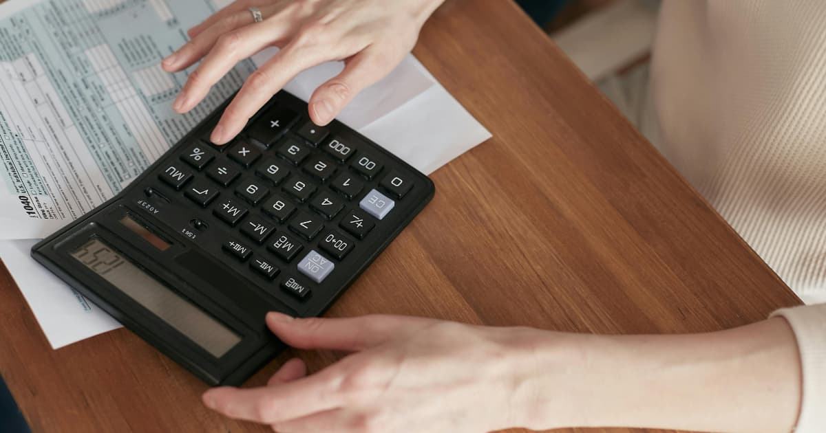 Hands using calculator with tax documents and financial paperwork