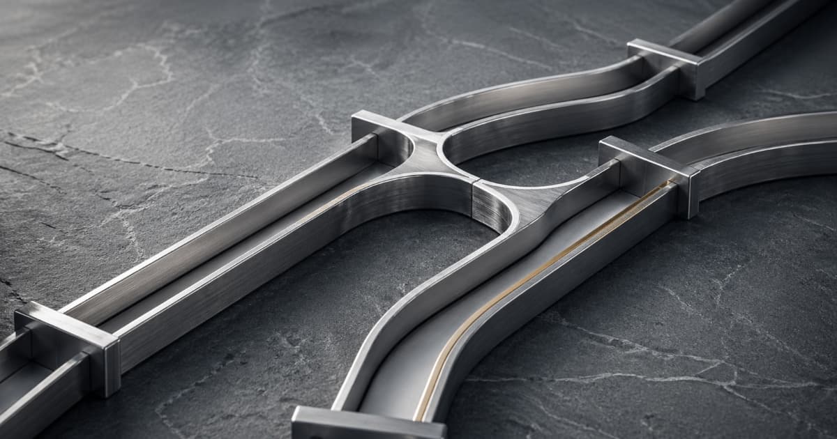 Brushed metal split channels on stone suggesting multiple payment routes, lit like a premium editorial product photo