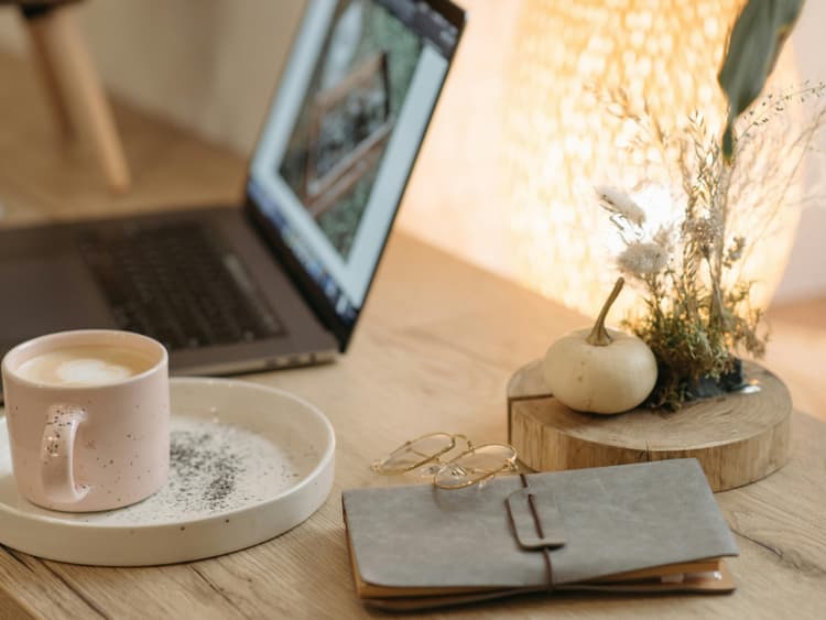 Curated freelancer workspace Cozy freelancer workspace with laptop, coffee, and leather notebook