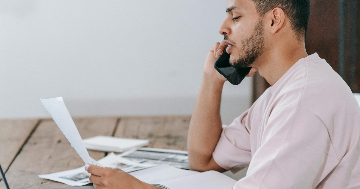 Freelancer reviewing invoice document while making a phone call about payment