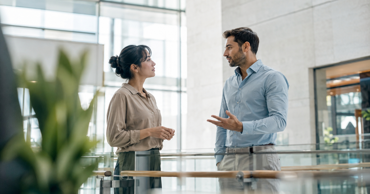 Two professionals discussing terms in a bright modern lobby, framed by soft natural window light