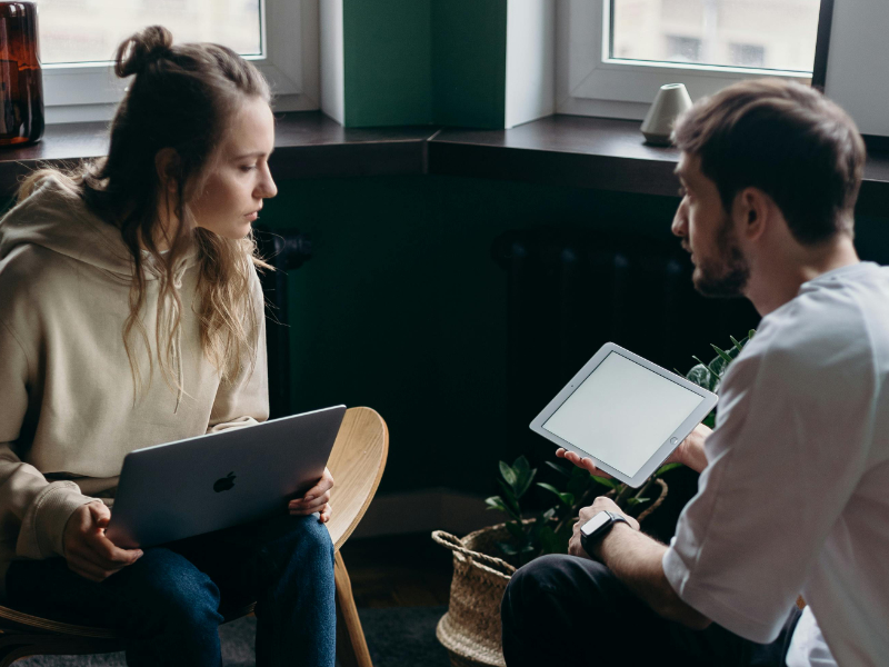 Two freelancers comparing invoicing apps on laptop and tablet